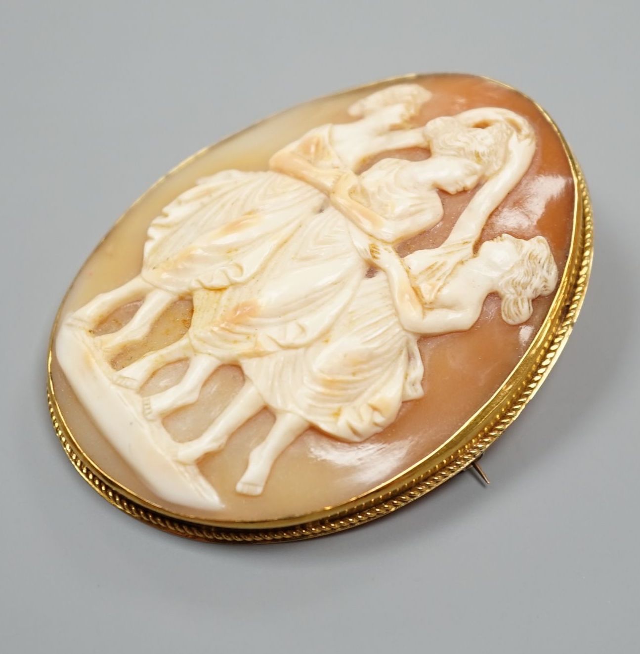 A yellow metal mounted oval cameo shell pendant brooch, carved with The Three Graces, 62mm, gross weight 21.4 grams.